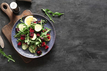 Plate of fresh salad with beet and cucumber on black background