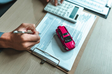 A car on reservation from and salesman hands write. Image represents the concept Insurance, protection, loan and guarantee.