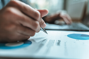 A close-up view of a businessman hand gripping a pen, indicating a project along with financial...