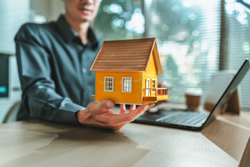 Home salesman, insurance salesman Holding a house in hand. Assets, real estate, loans and property concept.