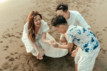 Families explore the sand, look at crabs, and find seashells on the beach during holidays, travel, long weekends, summers, or other vacations. They are happy to spend time together.