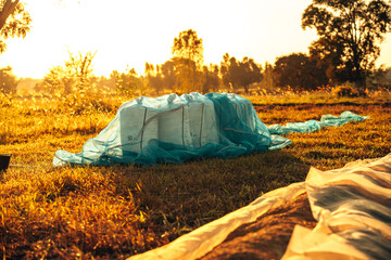 A collection of sacks resting in a tranquil countryside field, illuminated by a golden sunset, creating a serene agricultural scene. Paddy, grain, rice at industry sunset.