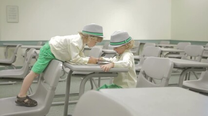 Young boy learning with tablet computer in classroom  - Powered by Adobe