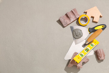 Trowel with cement, brick and construction tools on grey grunge background