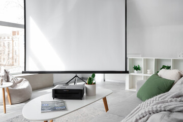 Interior of light living room with blank projector screen, sofa and table