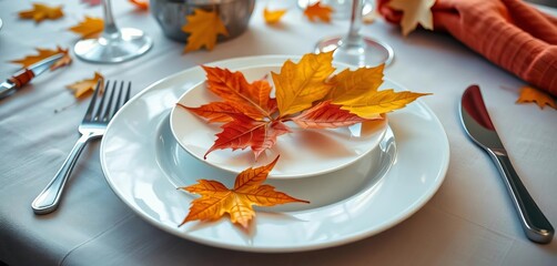 A plate rests on a neatly set table, adorned with several fallen autumn leaves, red, food