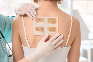 Female doctor applying mustard plaster on patient's back in clinic, closeup