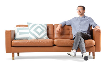 Fototapeta premium Handsome young man sitting on brown sofa against white background