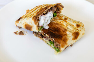 Close-up of a delicious shawarma wrap held in hand