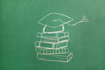 Drawn graduation hat with books on green chalkboard