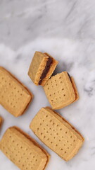 A close-up of handmade chocolate sandwich cookies tied with rustic twine, neatly stacked on a wooden plate. The golden brown biscuits with rich chocolate filling evoke a warm, homemade feel. Styled in