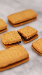 A close-up of handmade chocolate sandwich cookies tied with rustic twine, neatly stacked on a wooden plate. The golden brown biscuits with rich chocolate filling evoke a warm, homemade feel. Styled in