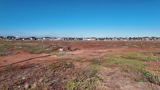 Aintree, Melbourne, Australia-a large undeveloped land bordered by rows of new houses. Early-phase land clearing and vacant plot supply for future suburban residential development in outer suburbs