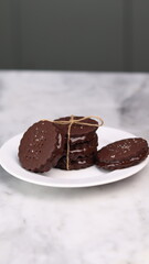 chocolate cookies arranged on a white plate with a marble table background