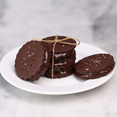 chocolate cookies arranged on a white plate with a marble table background