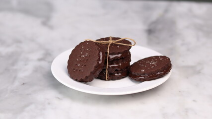 chocolate cookies arranged on a white plate with a marble table background