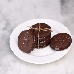chocolate cookies arranged on a white plate with a marble table background