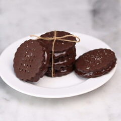 chocolate cookies arranged on a white plate with a marble table background