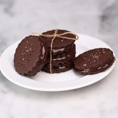 chocolate cookies arranged on a white plate with a marble table background