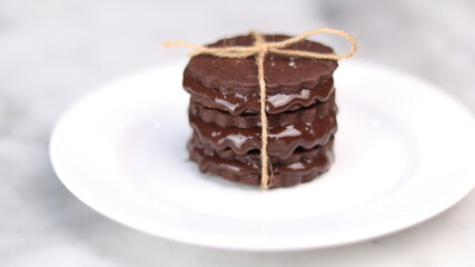 chocolate cookies arranged on a white plate with a marble table background