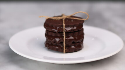chocolate cookies arranged on a white plate with a marble table background