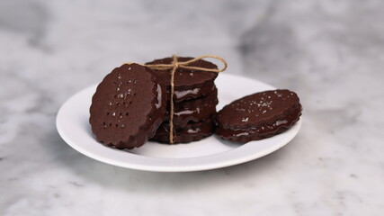 chocolate cookies arranged on a white plate with a marble table background