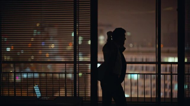 Angry man silhouette calling cellphone dark office window. Businessman yelling