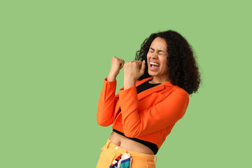 Happy young African-American woman in stylish blazer on green background
