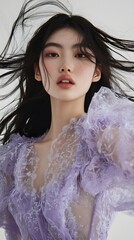 A young woman with long black hair in a light purple lace top.