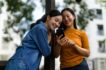 Two young women looking at smartphone and smiling outdoor