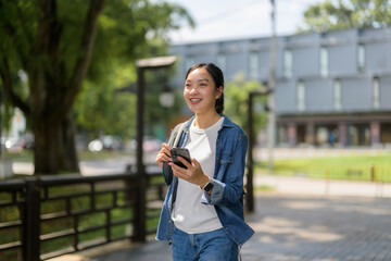 Smiling student walking in a park using a smartphone app