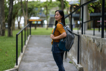 Portrait of young beautiful Asian woman student walking outdoors in university campus with backpack