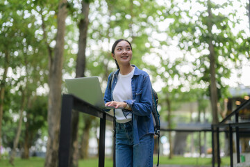 Young student using laptop in university campus park, enjoying outdoor study