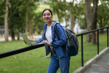 Smiling student using laptop in university campus park