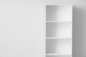 Empty bookshelf near light wall