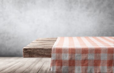 Rustic wooden table with a peach and white gingham tablecloth against a textured grey wall