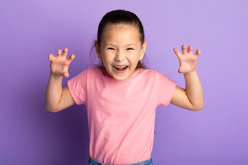 Funny Tiger. Portrait of cute playful little asian kid showing claws, purple studio background