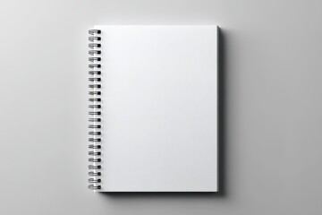 A blank, white spiral-bound notebook sits on a light gray surface, photographed from a high angle, showcasing its clean, minimalist design