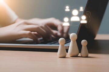 A person typing on a laptop with wooden figurines representing teamwork and collaboration in front of the screen.