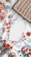 A cozy picnic setup with a wicker basket, red and blue checkered napkins, dried flowers, and a dessert on a white tablecloth.