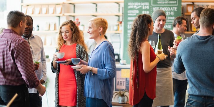 Group of people socializing at a cafe. Diverse group enjoying drinks, chatting, and smiling. Casual gathering with coffee and conversation in a cozy setting. Diverse people mingle at a social event. - Powered by Adobe
