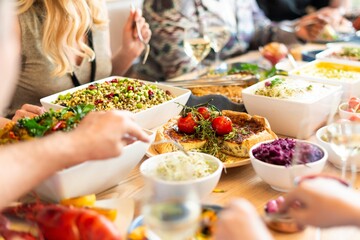 Vibrant meal setting with variety of food dishes, including salads, meats, and sides. People enjoy variety of foods, sharing a colorful and abundant feast together. Diverse people enjoy eating food
