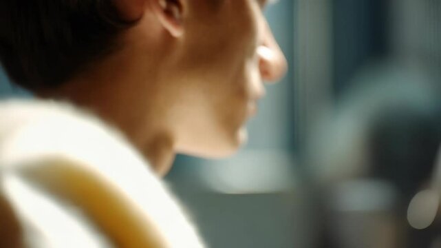 Close-up profile of a young adult's face with shallow depth of field and soft natural light focused on the face and skin.