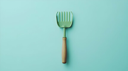 Vintage Green Rake With Wooden Handle On Light Teal Background