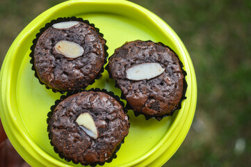 close up of Fudge Brownies with almonds on a green plate on a blurred background