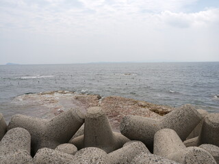 Rocky Japanese Coastline with Breakwaters and Blue Sky
