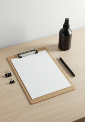 Blank Clipboard Mockup: A clean, minimalist mockup featuring a blank clipboard, pen, paper clips, and a black bottle on a light wood desk, perfect for branding and design projects.
