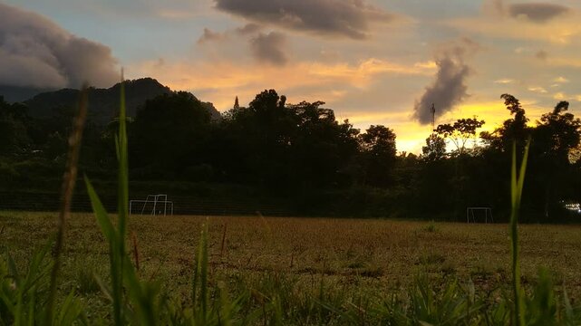 The beauty of sunrise on a field with mountains and clouds in the background