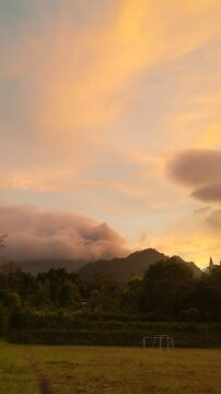 The beauty of sunrise on a field with mountains and clouds in the background