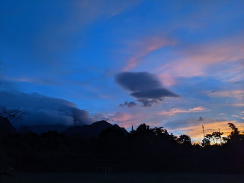 The beauty of sunrise on a field with mountains and clouds in the background